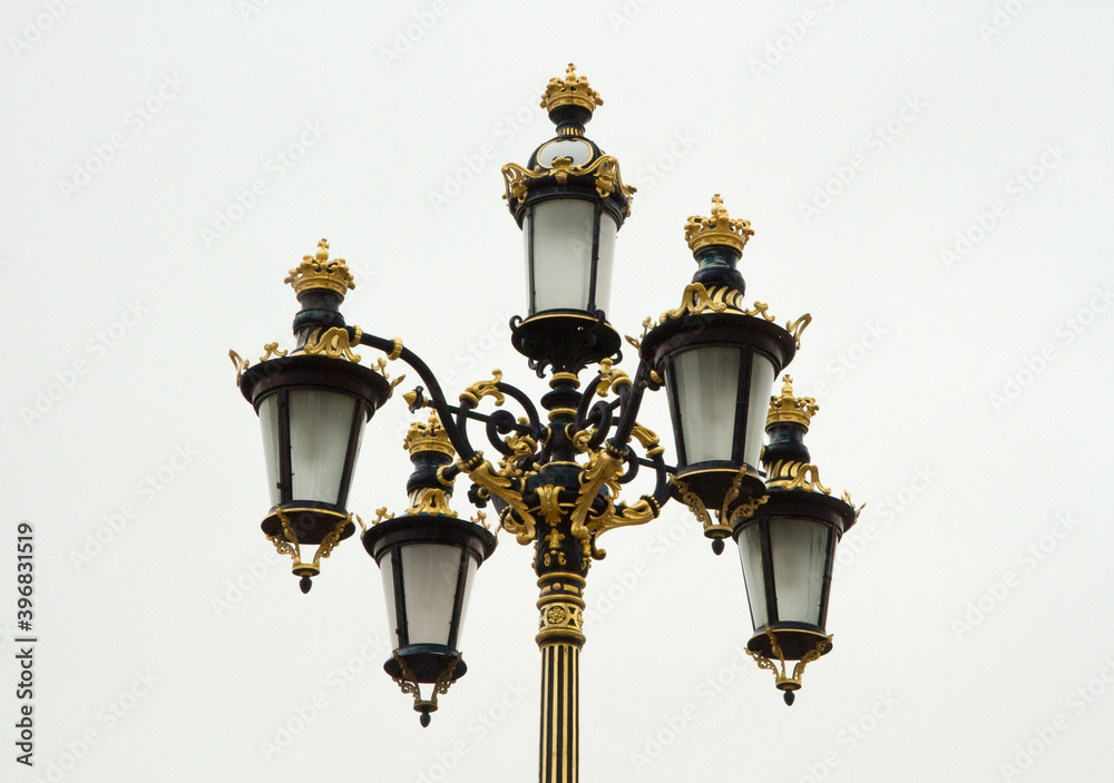 City lightning and illumination. Closeup view of beautiful street lights with baroque and rococo decoration in golden details in Madrid, Spain.   