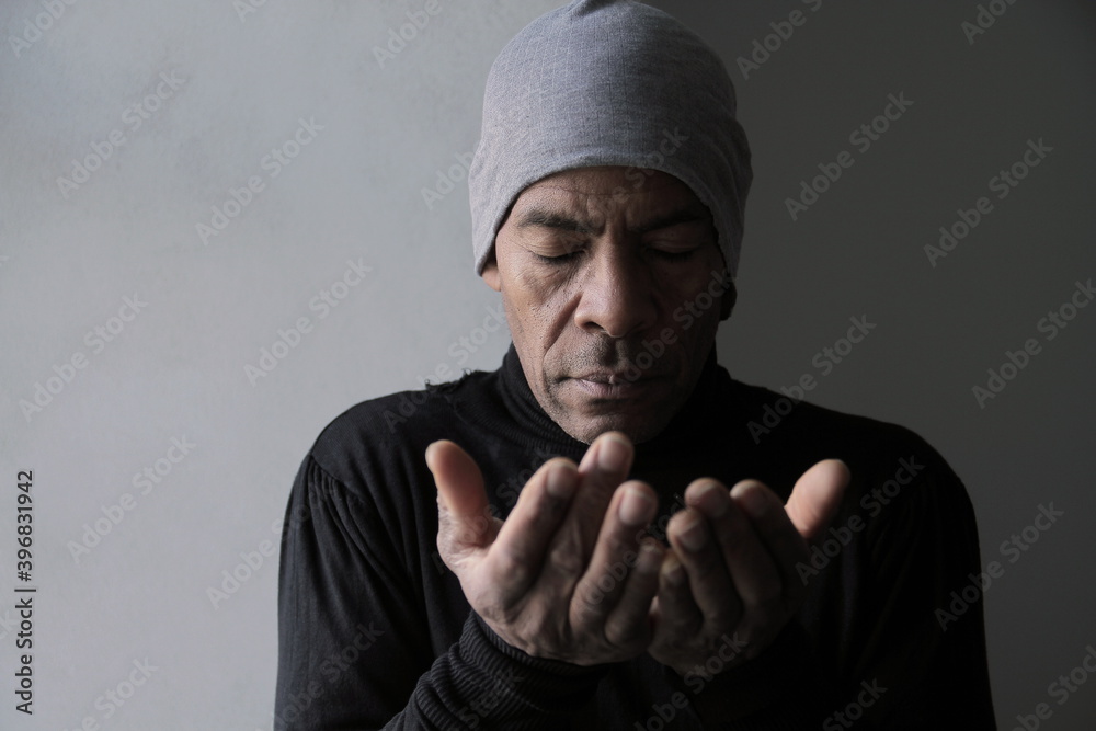 man praying to god with hands together Caribbean man praying with grey background stock photo man praying to god with hands together Caribbean man praying with grey background stock photo