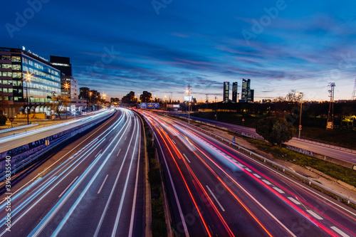 Highway A-1in Madrid Spain with car light trails at rush hour at sunset with Cuatro Torres Business area in the background photo