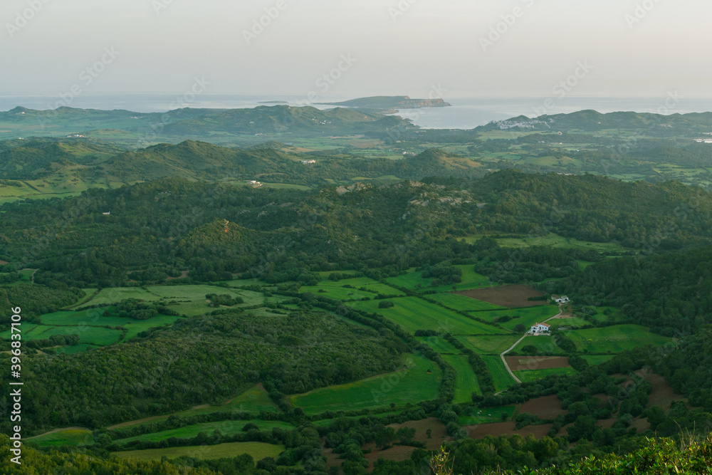 View of menorca from Monte Toro. Green fields and coast of the Mediterranean Sea in the distance. 