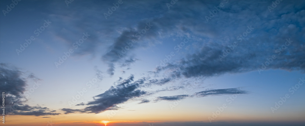 Fluffy clouds in evening sunset sky panoramic view. Climate, environment and weather concept cloudscape background.