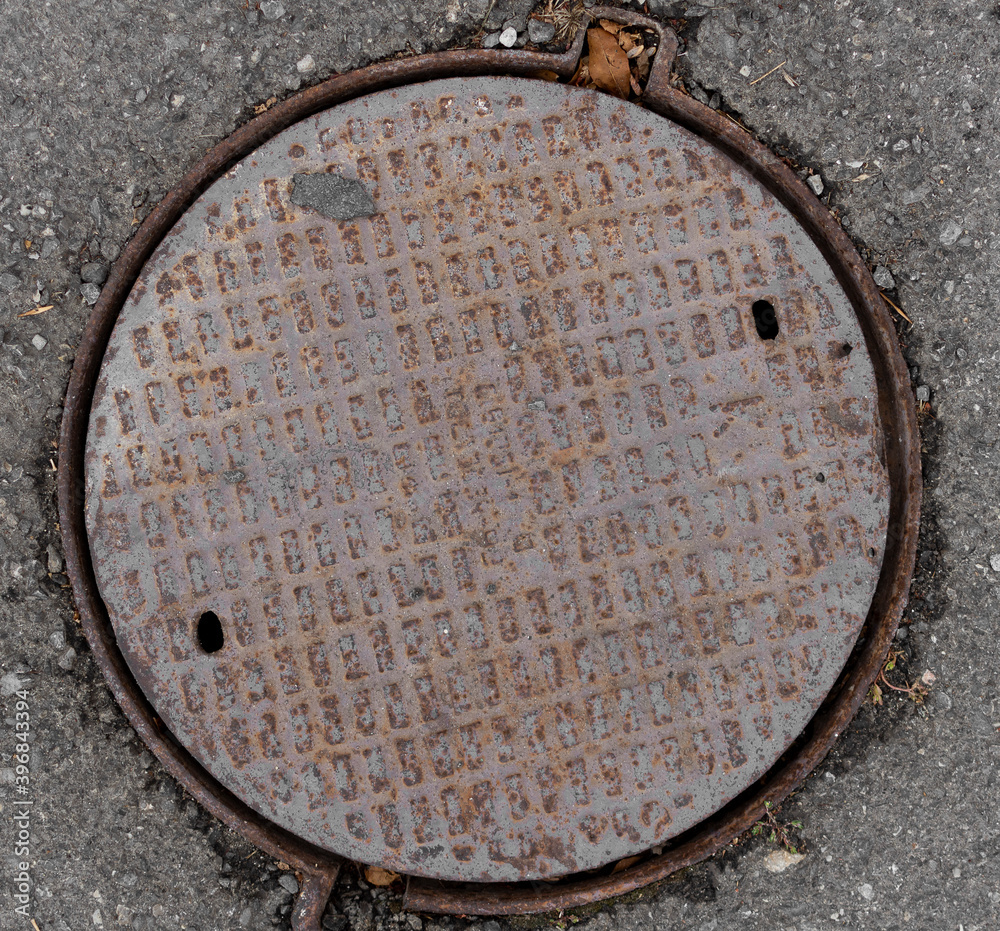 Old sewer manhole on the asphalt