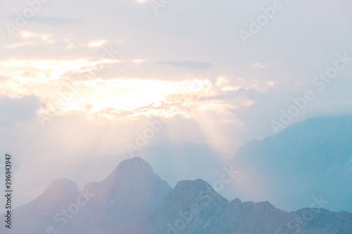 Sunset in the mountains, the sunbeams break through the clouds and illuminate the mountain.