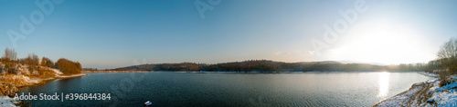 Panorama of winter lake with fog and forest