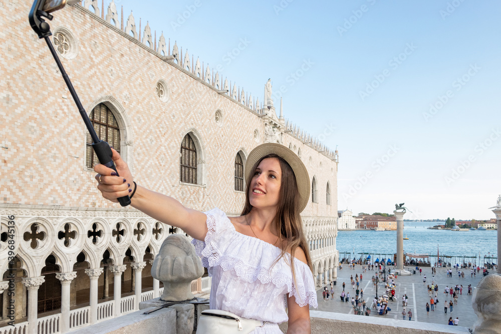 Pretty female taking fun self portrait photo in San Marco square in travel Europe city Italy, Venice. Panoramic view old Italian architecture with landmark bridge, romantic boat. Venezia.