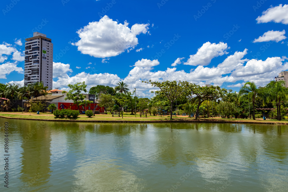 Paisagem do Parque Ipiranga na cidade de Anápolis em Goiás. Um parque com um lago, algumas árvores e céu azul com algumas nuvens.