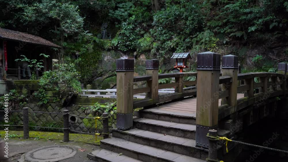 Male hiker walking over bridge in beautiful temple inside dark forest Male hiker walking over bridge in beautiful temple inside dark forest