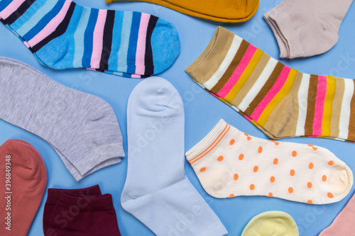 Many multicolored new socks stacked against a blue background. top view.