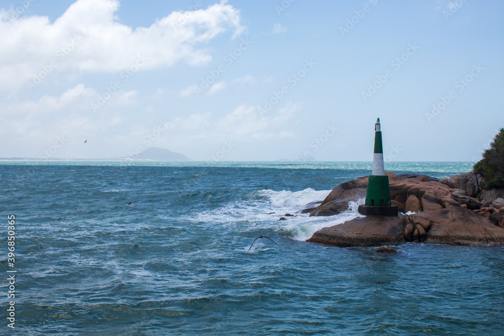 Rocks and the lighthouse of Canal da Barra in tropical beach, Praia da Barra da Lagoa, Florianopolis, Santa Catarina, Brazil, Florianópolis