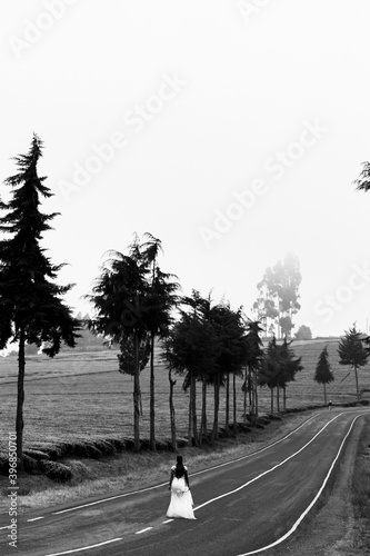 Woman Young Beautiful Lady Walking In Middle Of The Kenyan Highway Road  On A foggy misty day in the morning at the  Kiambu Limuru Highway  Kiambu County Kenya East Africa Trees On The Road Black And photo