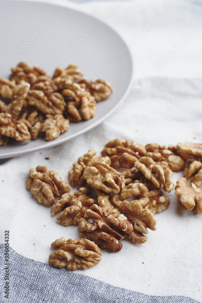 walnut kernels on a white blue tablecloth, craft paper and a gray round plate. ripe walnut fruit for vegenans walnut kernels on a white blue tablecloth, craft paper and a gray round plate. ripe walnut fruit for vegenans
