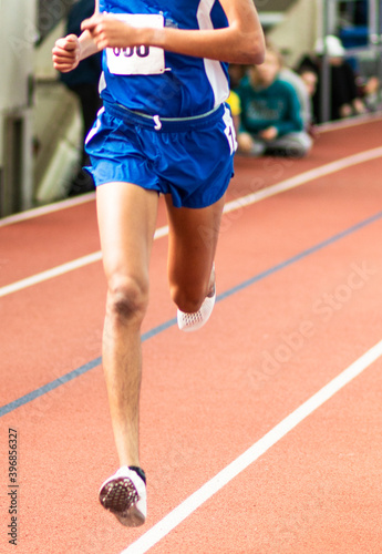 Runner racing on an indoor track in a blue uniform