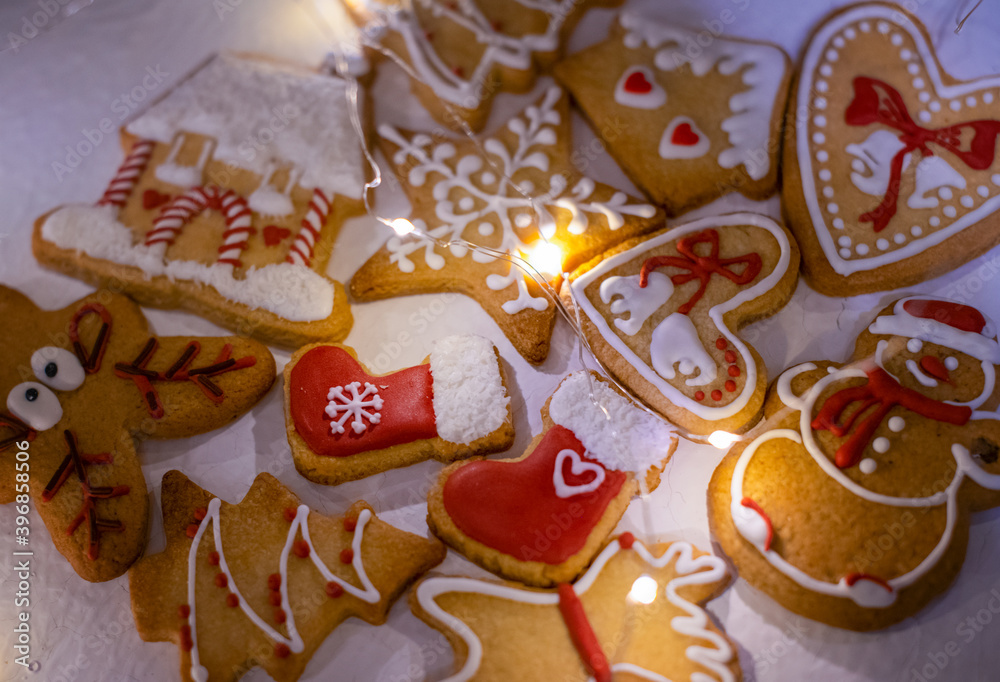 Gingerbread traditional gingerbread Christmas. Beautifully decorated with red and white glaze. Sweet dessert. Concept of celebration of festive holidays. Magic lights garlands.