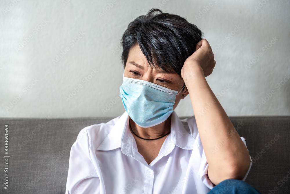 Straining Senior woman wearing face mask sitting on couch at her home during Corona virus crisis. Straining Senior woman wearing face mask sitting on couch at her home during Corona virus crisis.