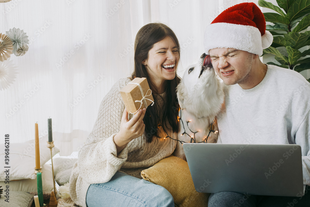 Happy family with cute dog and laptop exchanging christmas presents, celebrating holidays at home Happy family with cute dog and laptop exchanging christmas presents, celebrating holidays at home