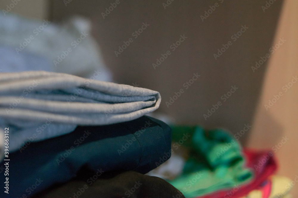 A stack of clothes is in the closet. A stack of clothes is in the closet.