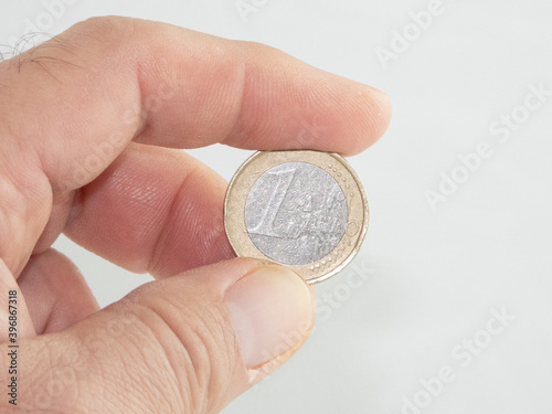 Palma de Mallorca, Spain, November 29, 2020: An adult man's hand holding a 1 euro coin isolated on white background. Illustrative editorial image.