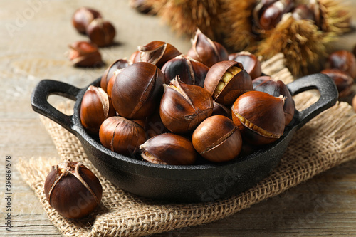 Tasty roasted edible chestnuts on wooden table, closeup
