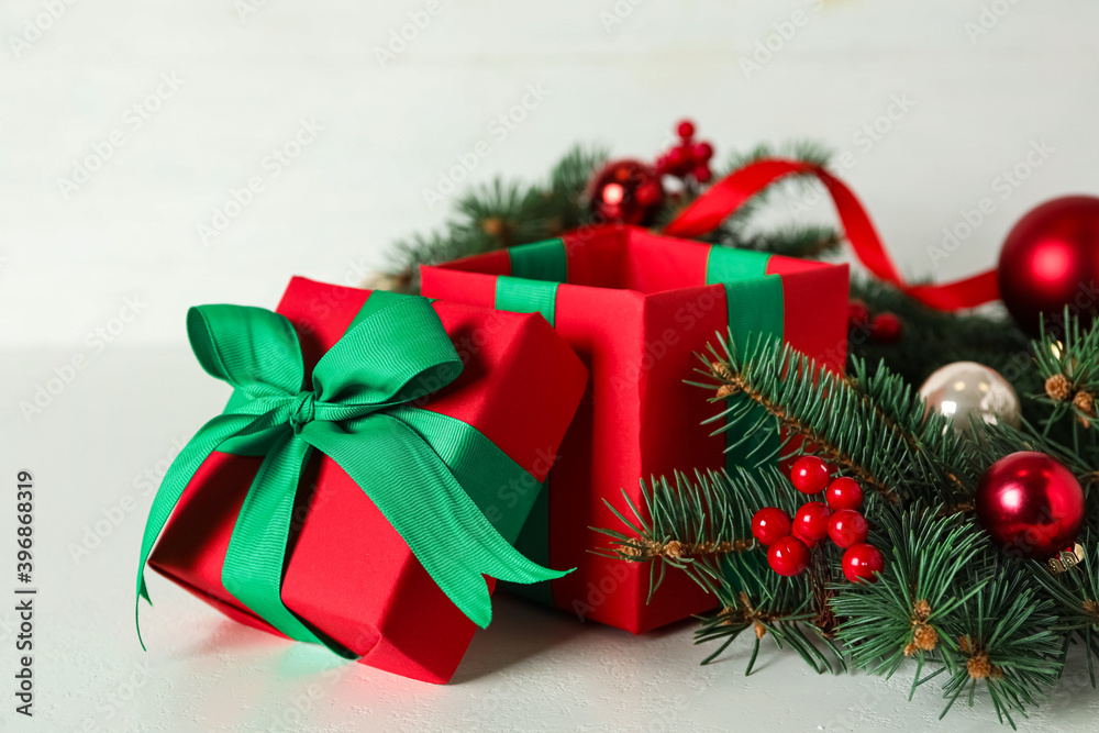 Red gift box with fir tree branches and Christmas balls on white table Red gift box with fir tree branches and Christmas balls on white table