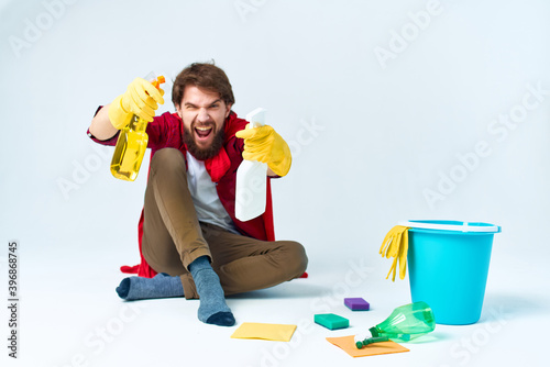 Man on the floor cleaning the house with cleaning supplies