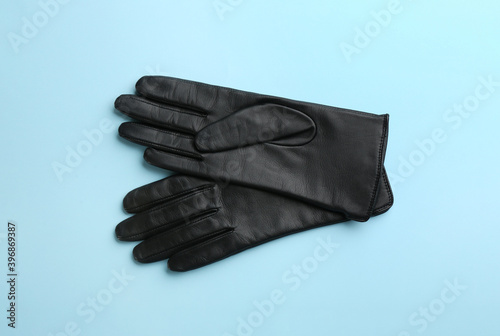 Pair of stylish leather gloves on light blue background, flat lay