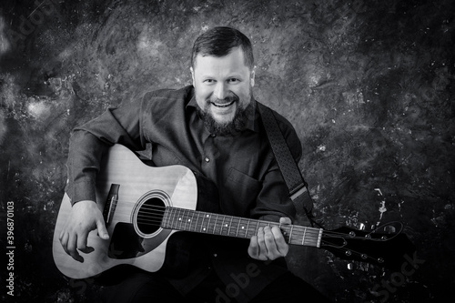 Mature musician plays acoustic guitar emotional studio portrait.