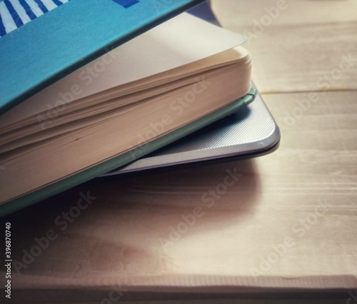 Turquoise closed notebook near laptop on wooden table