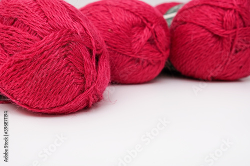 Red pink colorful skeins of yarn close up, fuchsia color woolen yarn for crochet and knitting, hobby and handmade concept, copu space
