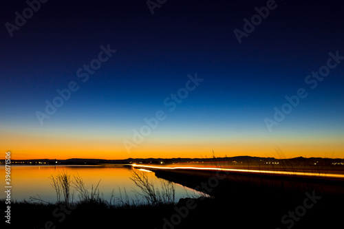 Water landscape with dark blue sky and fleeting light of cars in motion dusk sunset
