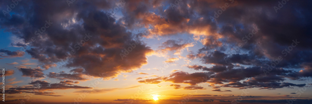 Dramatic sunset sky with clouds. Natural panorama of sky with setting sun.