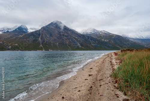 Quiet beach on the Tasermiut Fjord in front of beautiful snow-capped mountains