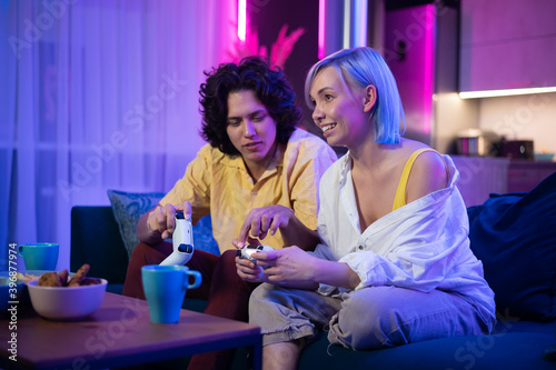 Handsome young man teaching how to play the video games to his girlfriend, on the couch, concept about home entertainment, video games. photo