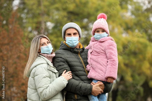 Family in medical masks outdoors on autumn day. Protective measures during coronavirus quarantine