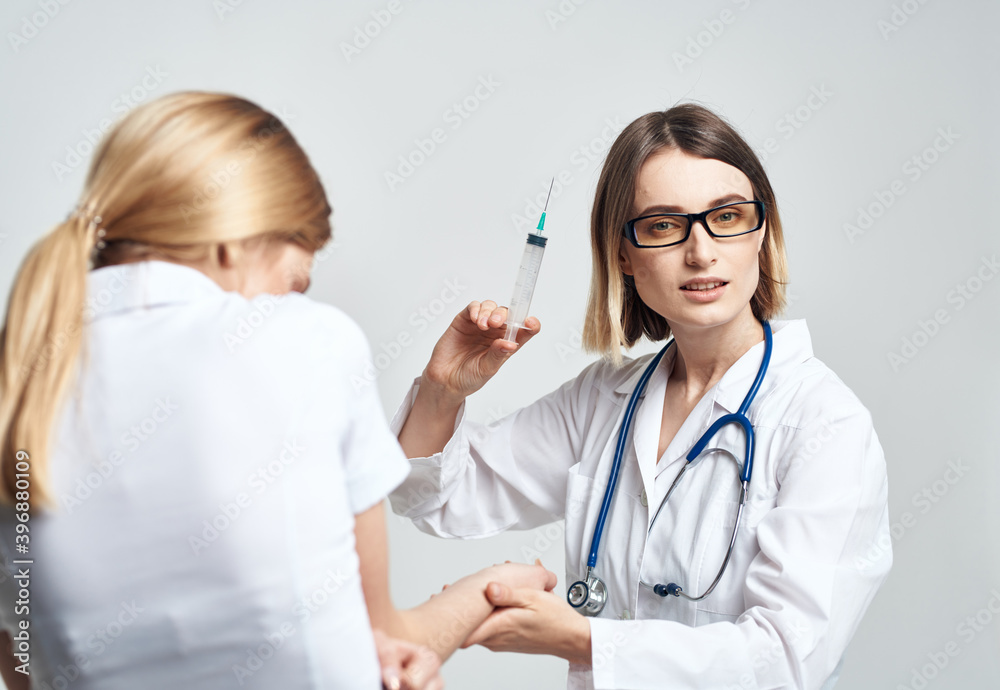 female doctor giving an injection to a scared female patient in a white t-shirt female doctor giving an injection to a scared female patient in a white t-shirt