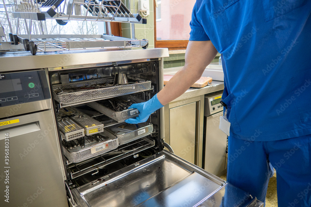 employee of a surgical department loads a washing machine with used surgical instruments