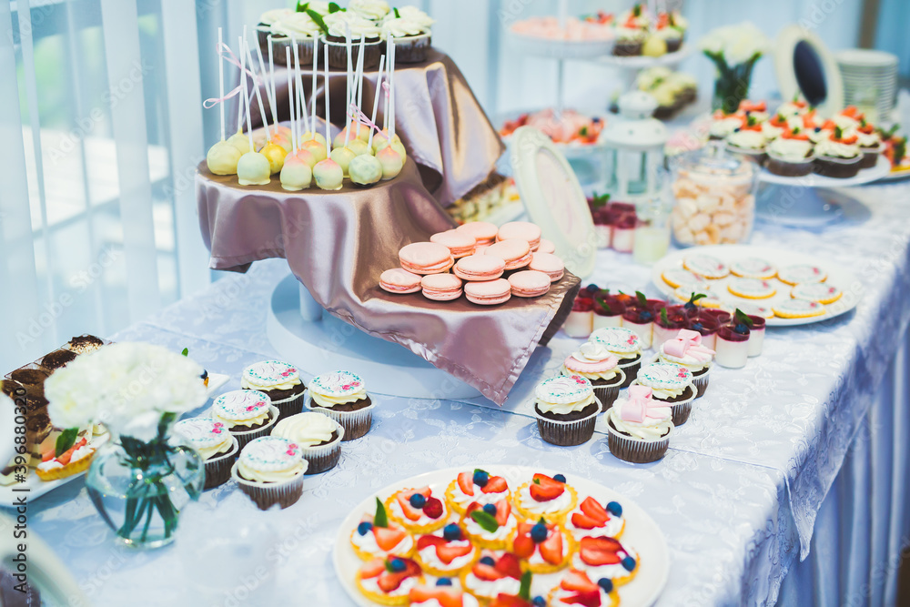 Delicious sweets on wedding candy buffet with desserts, cupcakes