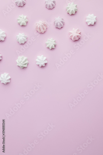 Colorful meringues on pastel pink background