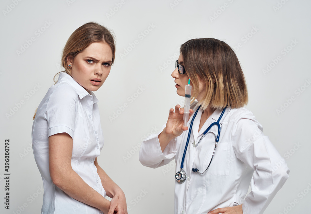 An outraged patient communicates with a nurse in a medical gown and a syringe in her hand An outraged patient communicates with a nurse in a medical gown and a syringe in her hand