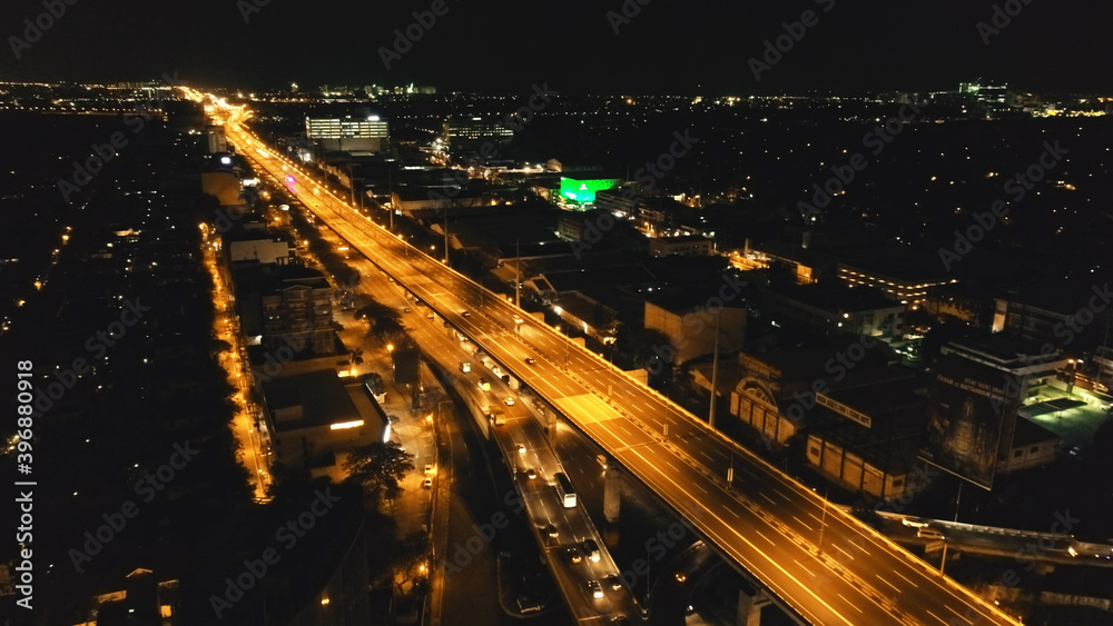 Closeup night traffic road with cars, trucks aerial. Philippines capital town of Manila cityscape. Urban scenery of metropolis city close up. Modern buildings with illuminated highway on bridge