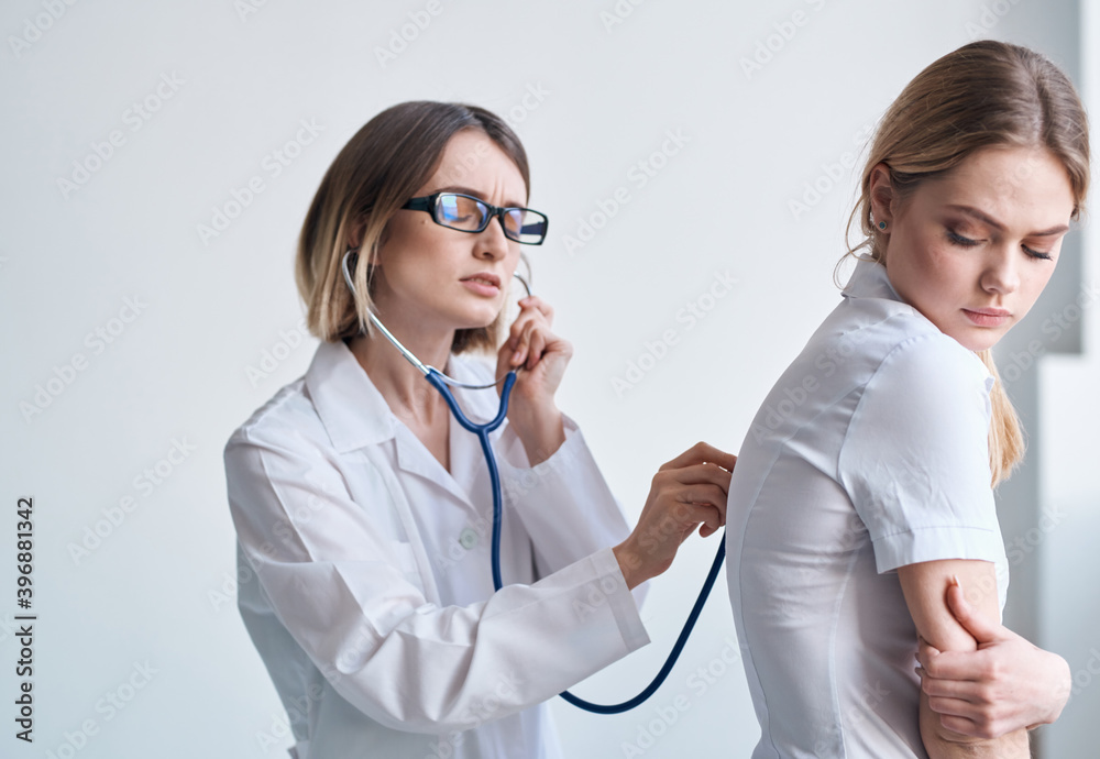 doctor in a medical gown with a stethoscope examines a patient on a light background doctor in a medical gown with a stethoscope examines a patient on a light background