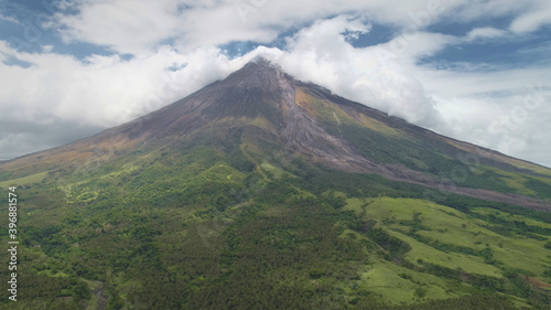 Aerial of volcano peak eruption clouds of haze. Hiking path at hillside green grass valley. Philippines countryside tourist attraction of Mayon Mount, Legazpi town. Nobody nature landscape at summer