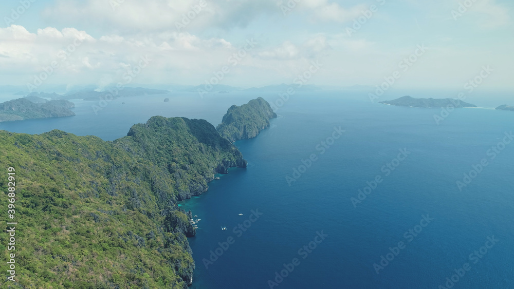 Amazing seascape of sea bay with rocks beach. Mountain island with green tropical forest at cliff ocean shore. Boats, vessels at blue coast water of El Nido Isles, Philippines, Visayas Archipelago