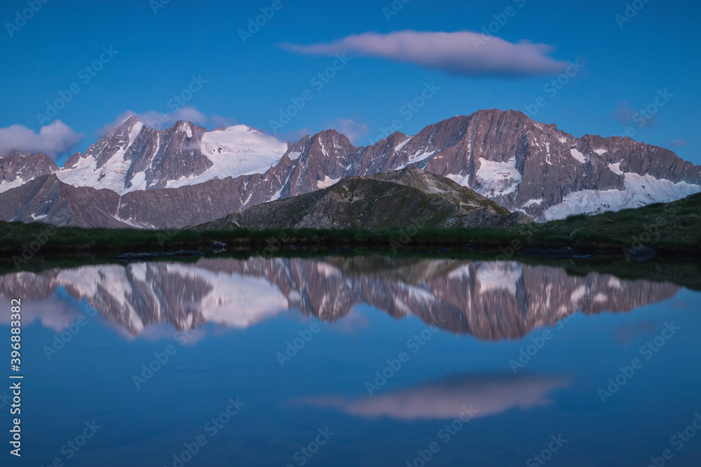 Alpine peaks reflected in mountain lake during blu hour, Stelvio National Park, Lombardia, Italy