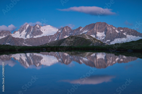 Alpine peaks reflected in mountain lake during blu hour, Stelvio National Park, Lombardia, Italy
