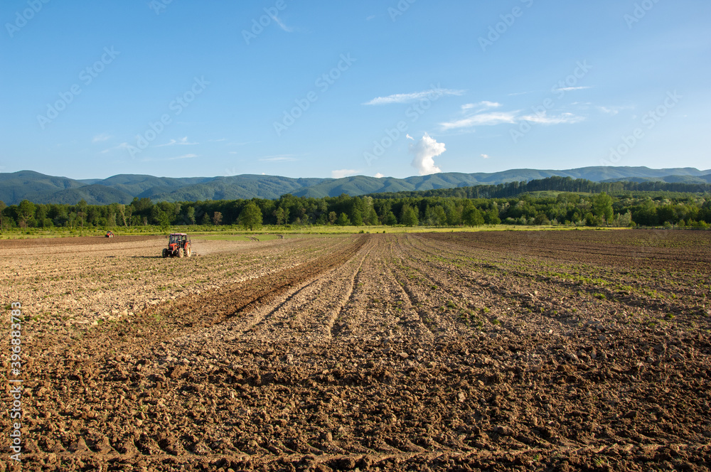Farming with tractor and plow in field with mountain Papuk in the background, Croatia Farming with tractor and plow in field with mountain Papuk in the background, Croatia