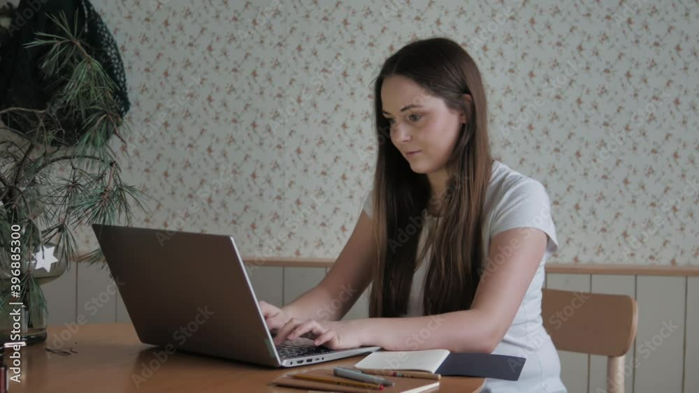 Smiling young woman sitting using laptop notebook looking at screen typing message notes, happy lady chatting on computer browsing surfing internet social media studying or working online at home Smiling young woman sitting using laptop notebook looking at screen typing message notes, happy lady chatting on computer browsing surfing internet social media studying or working online at home