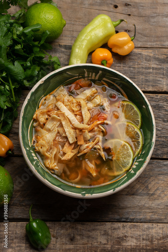 Mexican lime soup with chicken on wooden background photo