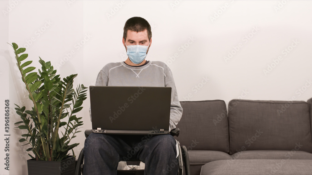 Man on wheelchair remotely working from home using laptop, looking at screen with virtual web chat. Man on wheelchair remotely working from home using laptop, looking at screen with virtual web chat.