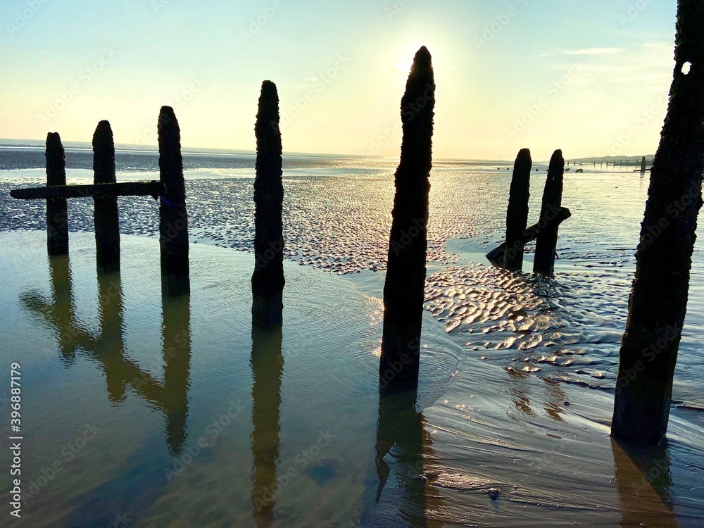 Winchelsea beach landscape view at low tide exposing flat sand with wooden sea groynes protruding from the sand Winchelsea beach landscape view at low tide exposing flat sand with wooden sea groynes protruding from the sand