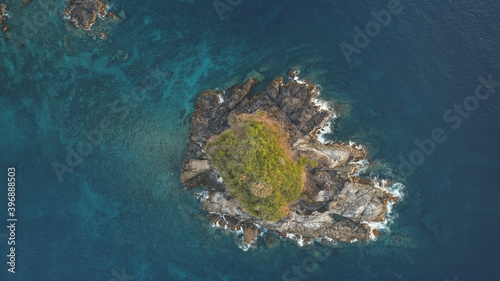 Top down of rock island with green peak aerial. Nobody nature landscape of El Nido Islet, Philippines, Asia. Ocean waves at cliffs. Epic sea bay with greenery isle. Tropical exotic trees at rock top